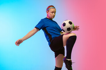 Bouncing ball. Female soccer, football player training in action isolated on gradient studio background in neon light. Concept of motion, action, ahievements, healthy lifestyle. Youth culture.
