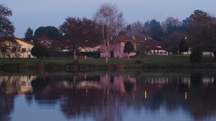 Obraz premium Pose longue d'un lac, avec des façades de maisons en arrière-plan, et un panache de fumée de cheminée