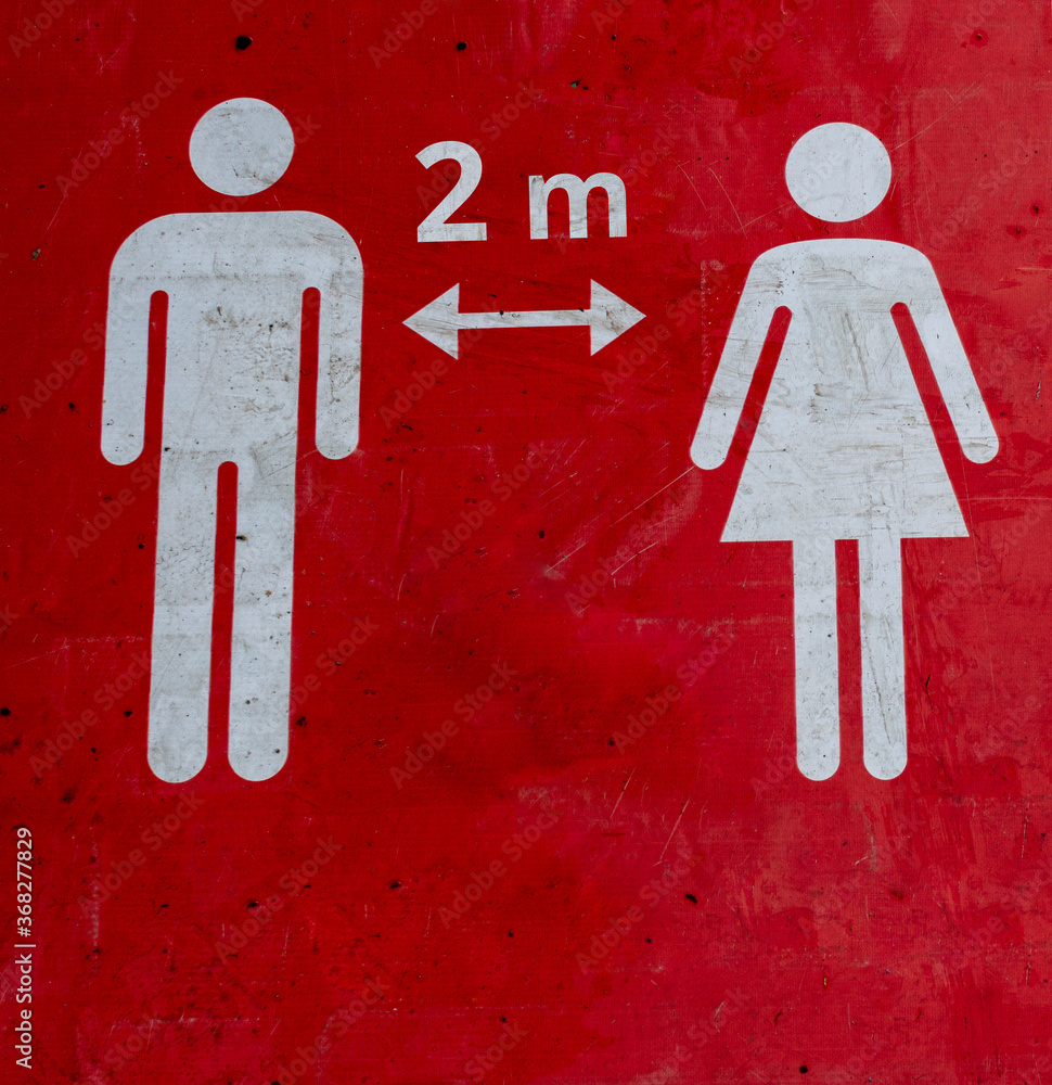 Wall mural red sign on the floor that informs people to keep 2 meter a social distance.the figures of a man and