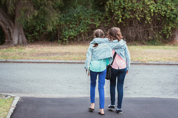 sisters or friends walking along hugging