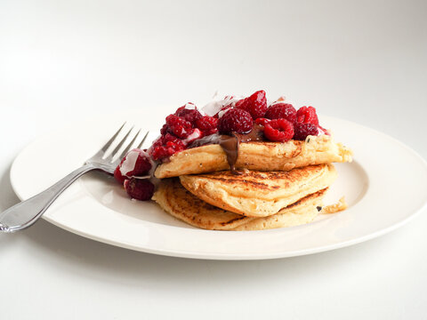Stacked pancakes with raspberries and chocolate coconut sauce