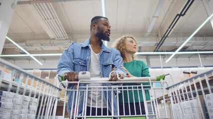 Low angle view of multicultural husband and wife buying materials for home decoration in diy store