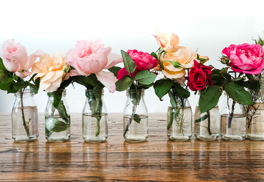 Roses in little bottle vases on the table.