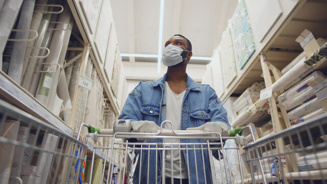 African Man Wearing Protection Facemask Choosing Wallpaper In Hardware Store.