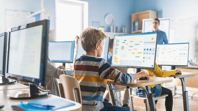 Elementary School Computer Science Classroom: Smart Little Schoolchildren Work On Personal Computers, Learn Programming Language For Software Coding. Schoolchildren Getting Modern Education. Back View