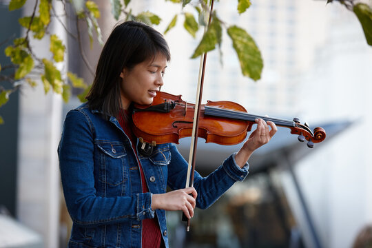 Young Asian female violin player practising outdoors