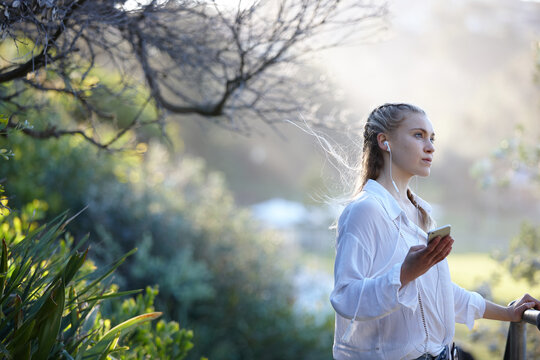 Young woman listening to music on smartphone while standing outdoors