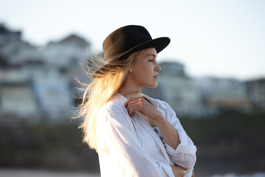 Carefree young blonde-haired woman at beach wearing black hat