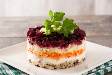 Traditional Russian herring salad with beetroot and carrots on wooden table	