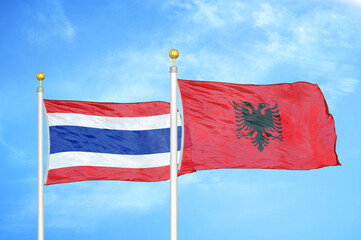 Thailand and Albania two flags on flagpoles and blue sky