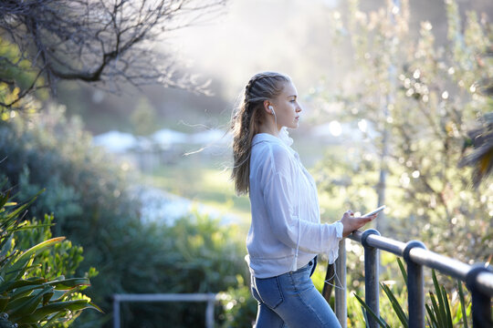 Young blonde-haired woman listening to music with earphones outdoors