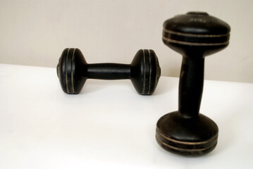 Obraz na płótnie Canvas A pair of black workout dumbbells isolated on white ground and grey wall using soft and selective focus .
