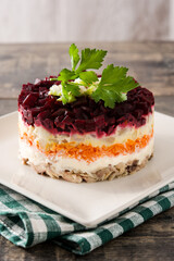 Traditional Russian herring salad with beetroot and carrots on wooden table	