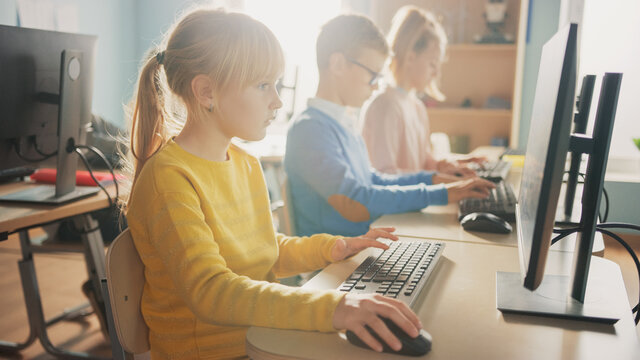 Elementary School Computer Science Classroom: Cute Little Girl Uses Personal Computer, Learning Programming Language for Software Coding. Schoolchildren Getting Modern Education.