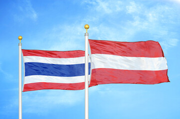 Thailand and Austria two flags on flagpoles and blue sky