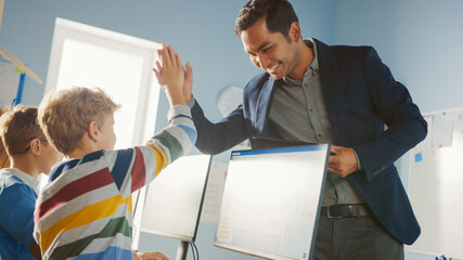 Elementary School Computer Science Classroom: Teacher Uses Tablet Computer, Explains Lesson to...
