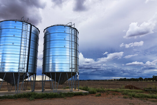 Two silos and farm land with storm clouds