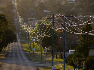 Sunlight on power lines looping off into the distance in a town