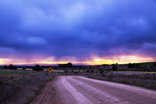 Stormy skies at sunset with car lights on road