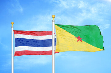 Thailand and French Guiana two flags on flagpoles and blue sky