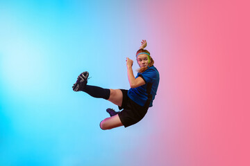 Obraz premium High jumping. Female soccer, football player training in action isolated on gradient studio background in neon light. Concept of motion, action, ahievements, healthy lifestyle. Youth culture.