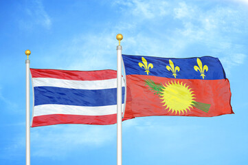 Fototapeta na wymiar Thailand and Guadeloupe two flags on flagpoles and blue sky