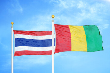 Thailand and Guinea two flags on flagpoles and blue sky