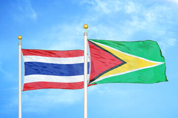 Thailand and Guyana two flags on flagpoles and blue sky