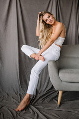 girl model blonde sitting on the couch in white clothes