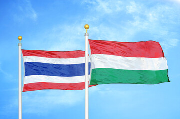 Thailand and Hungary two flags on flagpoles and blue sky