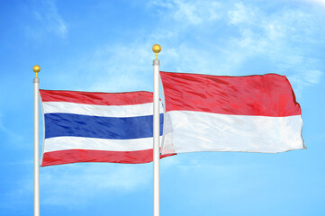 Thailand and Indonesia two flags on flagpoles and blue sky