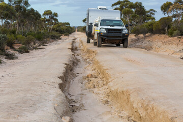 Vehicle towing caravan along flood-damaged road