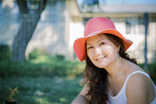 A Woman Wearing A Pink Hat In Her Backyard Enjoying Sunshine