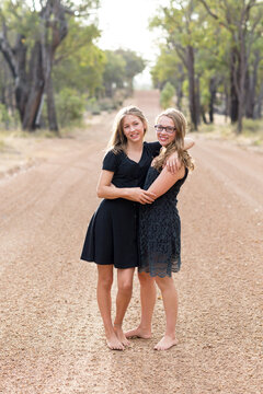 Happy teenage girls barefoot on country road