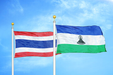 Thailand and Lesotho two flags on flagpoles and blue sky