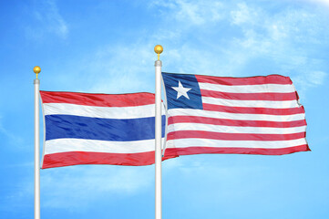 Obraz premium Thailand and Liberia two flags on flagpoles and blue sky