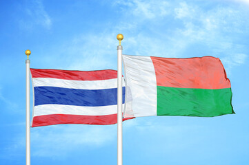 Thailand and Madagascar two flags on flagpoles and blue sky