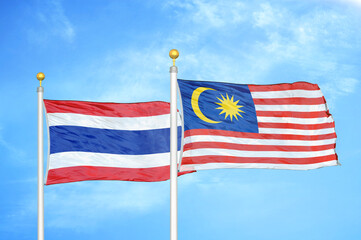 Thailand and Malaysia two flags on flagpoles and blue sky