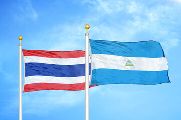 Thailand and Nicaragua two flags on flagpoles and blue sky