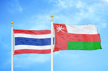 Thailand and Oman two flags on flagpoles and blue sky