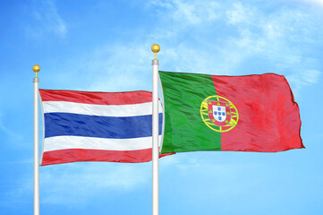 Thailand and Portugal two flags on flagpoles and blue sky