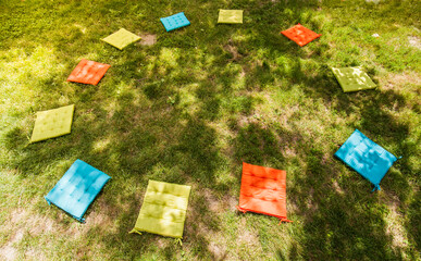 Colorful seat cushions in a circle. Child's play outdoors. Seating circle in nature. Bunte...