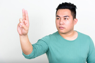 Portrait of young handsome overweight Asian man touching something