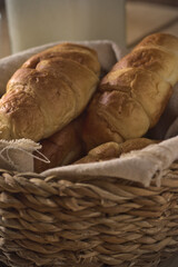 croissant recién horneados sobre un cesto de mimbre en una mesa con café y leche, listo para tomar en desayuno o merienda