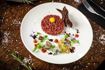 Fototapeta na wymiar Steak tartare. Horseradish creme, black bread, baguette chips on white plate. Delicious healthy raw meat food closeup served on a table for lunch in modern cuisine gourmet restaurant.