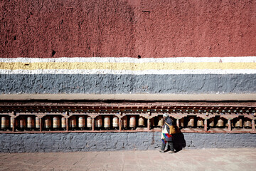 A Buddhist pilgrim turns prayer wheels at Sakya monastery, Tibet Autonomous Region, Tibet.