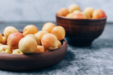 Lots of ripe yellow apricots close up in a crockery on the table