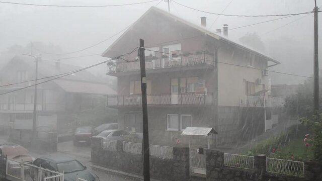 Heavy rain storm against houses. Rain shower in summer. Storm. Rain drops. 