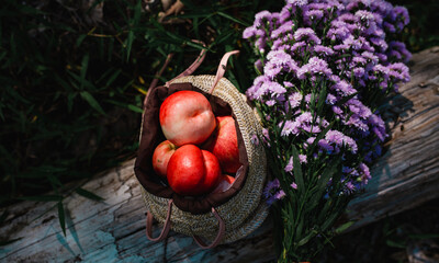 Fresh red peach in straw shopping bag and Purple flower.