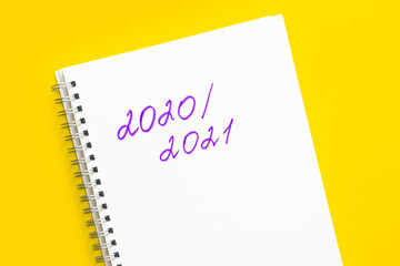 Back to school. Concept of the new school year and return to school. The inscription 2020 - 2021 in a white notebook with a spiral, on a yellow background.